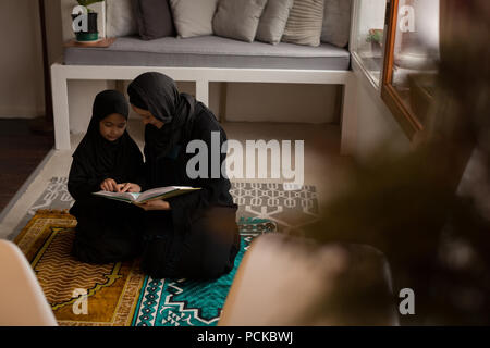 Muslimische Mutter Unterstützung ihrer Tochter heiligen Quran zu lesen Stockfoto