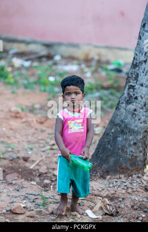 PONDICHERY, PUDUCHERRY, Tamil Nadu, Indien - März circa, 2018. Nicht identifizierte kleinen indischen barfüssigen Jungen in abgenutzt schlechte Kleidung spielen mit einem Kunststoff Stockfoto