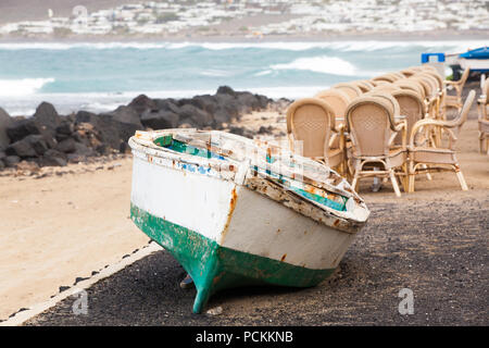 Caleta de Famara, Lanzarote, Palma/Spanien: Angeln Boot an Land und leeren Restaurant im Freien, mit dem Meer im Hintergrund Stockfoto