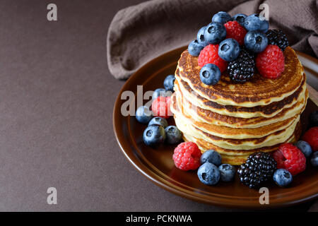 Stapel Pfannkuchen mit frischen Heidelbeeren, Himbeeren und Blackberry auf braune Platte Stockfoto