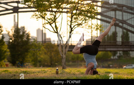 Sommertag. Junge sportliche schwangere Frau macht Handstand mit Splits. Übung im freien Training. Übung für balance, Yoga, Training. Gesunde Lebensweise. Stockfoto