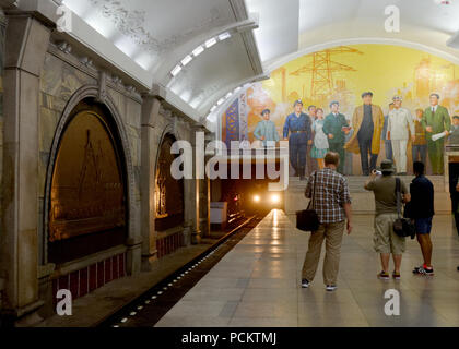 Touristen beobachten, eine U-Bahn zu fotografieren, wie es in der Erweckung Bahnsteig ankommt, Metro, Nordkorea Pjöngjang Stockfoto