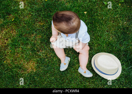 Blick von oben auf die schöne Baby Sitting auf dem Gras gekleidet im Vintage-Look Stockfoto