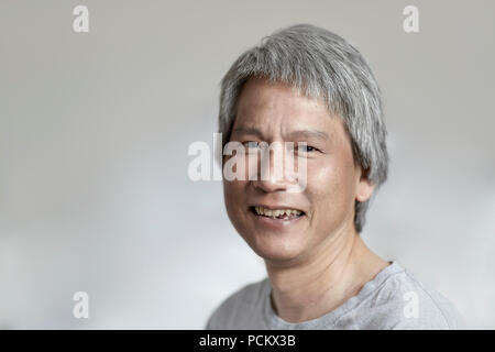 Porträt eines chinesischen Mann mit Grau, mit Blick auf die Kamera und lächelnd mit geringer Tiefenschärfe Stockfoto