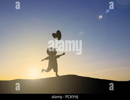 Silhouette Kinder spielen herzförmige Luftballons mit Sonnenuntergang Stockfoto