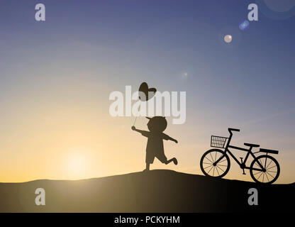 Silhouette Kinder spielen herzförmige Luftballons mit Sonnenuntergang Stockfoto