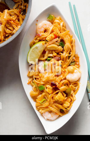 Pad Thai Nudeln mit Huhn, Garnelen, gemischter Salat, gehackten Erdnüssen, Schalotten & Lime Keil Stockfoto