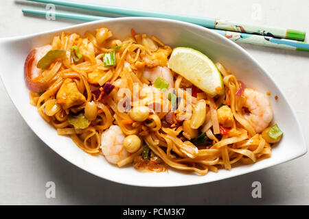 Pad Thai Nudeln mit Huhn, Garnelen, gemischter Salat, gehackten Erdnüssen, Schalotten & Lime Keil Stockfoto