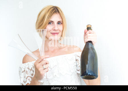 Schöne blonde Frau in weiß Top hält Wein Flasche und Gläser. Flasche Champagner. Schöne Weinfachmann/Sommelier. Partei Stockfoto