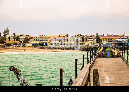 Lange pier, wandern Leute, Wohnhäuser auf Küste von Deutschen Kolonialstadt Swakopmund, Namibia Stockfoto