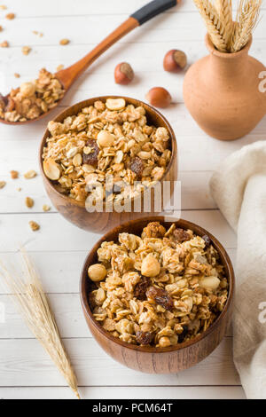 Trockene Frühstück der Hafer Flocken, Granulat und Muttern. Müsli in eine Tiefe hölzerne Platte Stockfoto