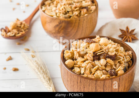 Trockene Frühstück der Hafer Flocken, Granulat und Muttern. Müsli in eine Tiefe hölzerne Platte Stockfoto