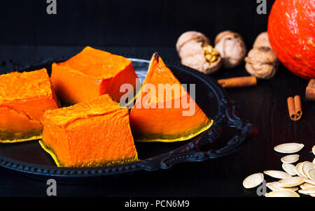 Gebratene Kürbisscheiben auf einem dunklen Platte, gesunden Snack Stockfoto