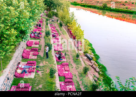Nicht identifizierte Personen sitzen in der Nähe von zehn eyed Brücke, eine beliebte Sehenswürdigkeit im Zentrum von Diyarbakir, Türkei. vom 16. Juli 2018 Stockfoto