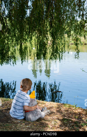 Kind im Park mit Plüsch Spielzeug Stockfoto