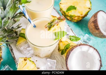 Erfrischende Sommerdrink, hausgemachte Pina Colada Cocktail, auf einem hellblauen Hintergrund, mit Stücken von Ananas, Kokos, Eis und Minze, Kopie Raum Stockfoto