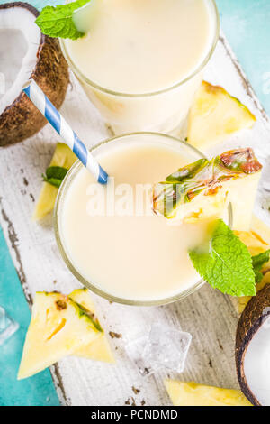 Erfrischende Sommerdrink, hausgemachte Pina Colada Cocktail, auf einem hellblauen Hintergrund, mit Stücken von Ananas, Kokos, Eis und Minze, Kopie Raum Stockfoto