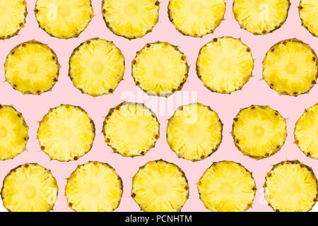 In Scheiben geschnittene Ananasstücke lag in Muster auf isolierte leicht rosa unterlegt. Muster der frisch geschnittene Ananas Obst auf lebhaften Hintergrund. Stockfoto