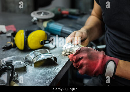 Männliche Metallbauer Montage Stück der mittelalterlichen Rüstung. Man Hände Behandeln von Metallen Teile der Hardware in einem Workshop Stockfoto