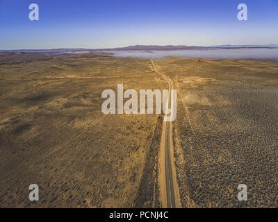 Landstraße, die durch die australische Outback Wüste, Berge, die unter niedrigen Cloud-Luftbild Stockfoto