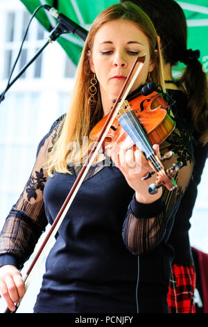 Kaukasische Frau, 20s, spielen Geige, Violine am Open Air Konzert. Französische folk rock Band Triskelles Durchführen einer open-air-Gig Stockfoto