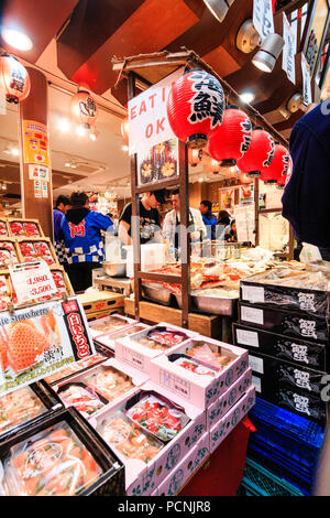 : Kuromon Ichiba, essen Markt in Osaka. Fish mongers Zähler verpackten Kartons abgepackte Seafoods. Reihe von chochin, rotes Papier Laternen hängen. Stockfoto