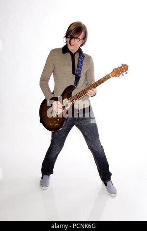 Junge männliche Kaukasischen Gitarrist in seinem frühen 20s in schwarzen Jeans spielen eine elektrische Gitarre voll Körper geschossen. Stockfoto