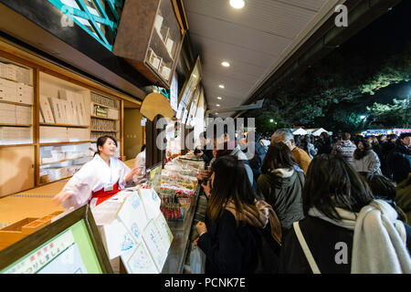 Shogatsu, neues Jahr, Nishisnomiya Schrein, Japan. Menschen kaufen Glücksbringer, des, von Miko, Schrein Dirnen, am Schrein Büro nach Mitternacht. Stockfoto