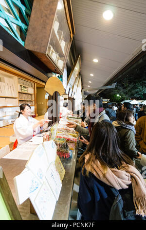 Shogatsu, neues Jahr, Nishisnomiya Schrein, Japan. Menschen kaufen Glücksbringer, des, von Miko, Schrein Dirnen, am Schrein Büro nach Mitternacht. Stockfoto