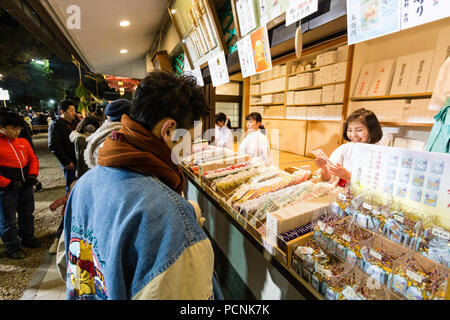 Shogatsu, neues Jahr, Nishisnomiya Schrein, Japan. Menschen kaufen Glücksbringer, des, von Miko, Schrein Dirnen, am Schrein Büro nach Mitternacht. Stockfoto