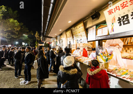 Shogatsu, neues Jahr, Nishisnomiya Schrein, Japan. Menschen kaufen Glücksbringer, des, von Miko, Schrein Dirnen, am Schrein Büro nach Mitternacht. Stockfoto