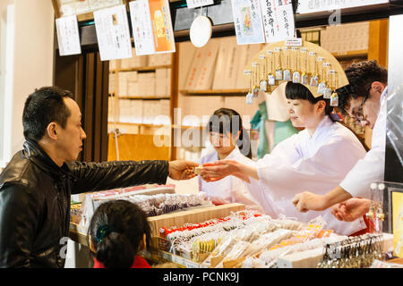 Shogatsu, neues Jahr, Nishisnomiya Shinto Schrein, Japan. Shrine Maiden, Miko, Übergabe Glücksbringer, des beim Kunden bis kurz nach Mitternacht. Stockfoto