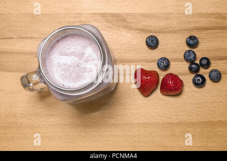 Berry Smoothie in einem Marmeladenglas mit Erdbeeren und Heidelbeeren auf Stockfoto