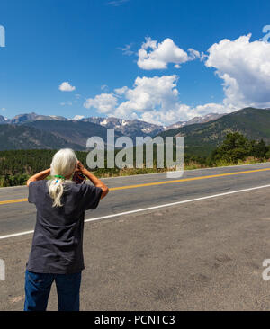 ESTES PARK, CO, USA-17 Juli 18: eine grauhaarige Frau mit an der Rückseite der Kamera, eine Kamera Bild von Gipfeln im Rocky Mountain N.P. Stockfoto