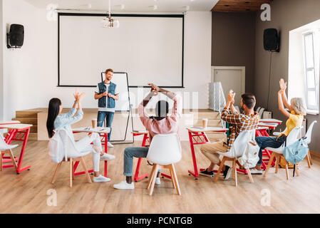 Ansicht der Rückseite des multiethnischen junge Schüler klatschend zu Dozent nach der Präsentation an der Hochschule Stockfoto