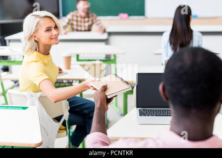 Ansicht der Rückseite des jungen Studenten teilen Notebook im Klassenzimmer während der Lektion Stockfoto