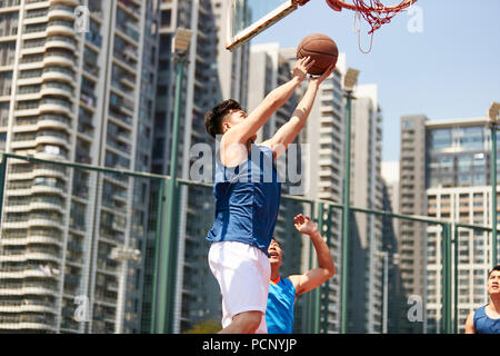Jungen asiatischen Basketball Spieler gehen, für ein layup während Gegner spielen Verteidigung. Stockfoto