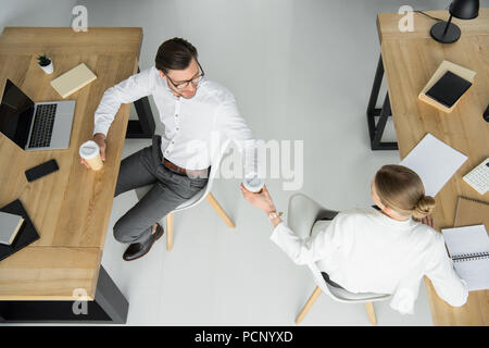 Ansicht von oben der jungen Kollegen mit Papier Tassen Kaffee sitzen im Büro Stockfoto