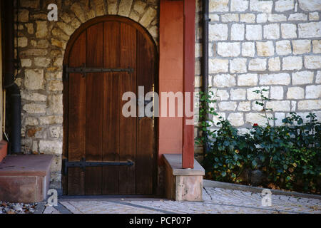 Eine schwere hölzerne Kirche Tür mit schmiedeeisernen Scharnieren. Stockfoto