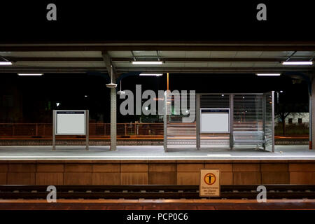 Die Plattform der Weinheimer Bahnhof bei Nacht mit Sitzen auf einem Glas Trennwand Stockfoto