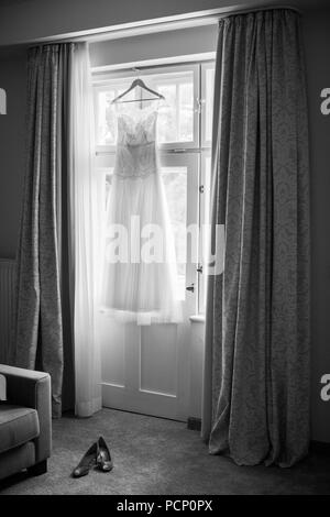 Hochzeit Kleid hängen am Fenster, Schuhe auf dem Boden, b/w Stockfoto