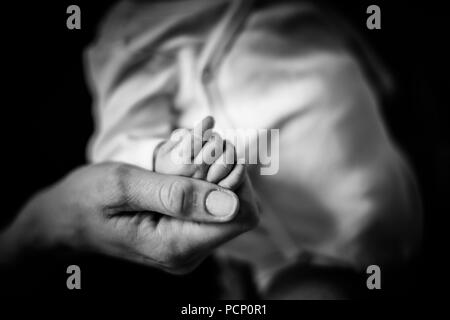 Mutter hand Ihres Babys halten, sanft, zärtlich, Nahaufnahme, Detail, Hintergrund unscharf, b/w Stockfoto