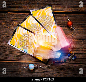 Tarot Karten, Pendelwerkzeug und Kristalle auf einem Holzbrett Stockfoto