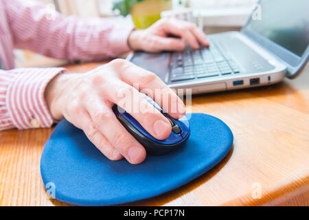 Mann im Heimbüro arbeiten mit Laptop, Computer Maus im Vordergrund Stockfoto
