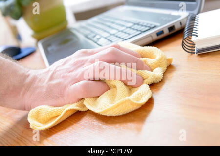 Hand Reinigung Schreibtisch mit gelben Tuch zu Hause Stockfoto