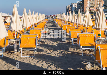 Reihen von orange Sonnenschirme und Liegestühle am Strand von Igea Marina in der Nähe von Rimini Stockfoto