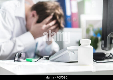 Traurig, betonte, traurig und unglücklich Arzt Abdeckung zeigen im Krankenhaus. Depressionen, Burnout, Stress und Druck von zu viel Arbeit. Stockfoto