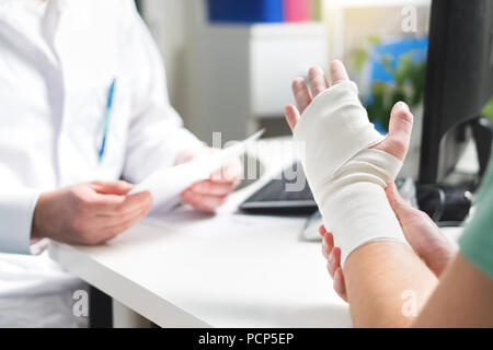 Verletzte Patienten, Arzt gebrochenes Handgelenk und Arm mit Bandage im Krankenhaus oder in der Notaufnahme. Verstauchung, Spannungsbruch oder repetitive strain. Stockfoto