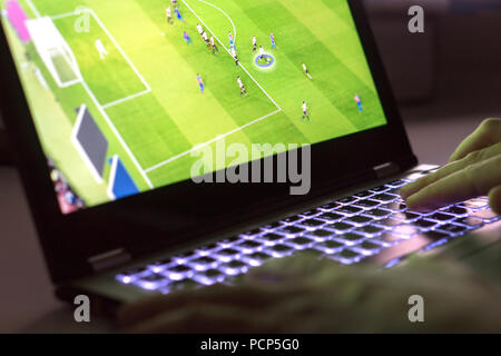 Junge Mann spielt Videospiel mit Laptop. Online Fußball oder Football Spiel in Computer. In der Nähe der Hände auf der Tastatur des Computers. Stockfoto