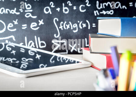 Moderne Bildung und e-Learning in der Schule Klassenzimmer Tabelle. Stapel von Büchern, Tablet und Stifte mit Blackboard voll oder Schreiben. Digitale Lehre. Stockfoto